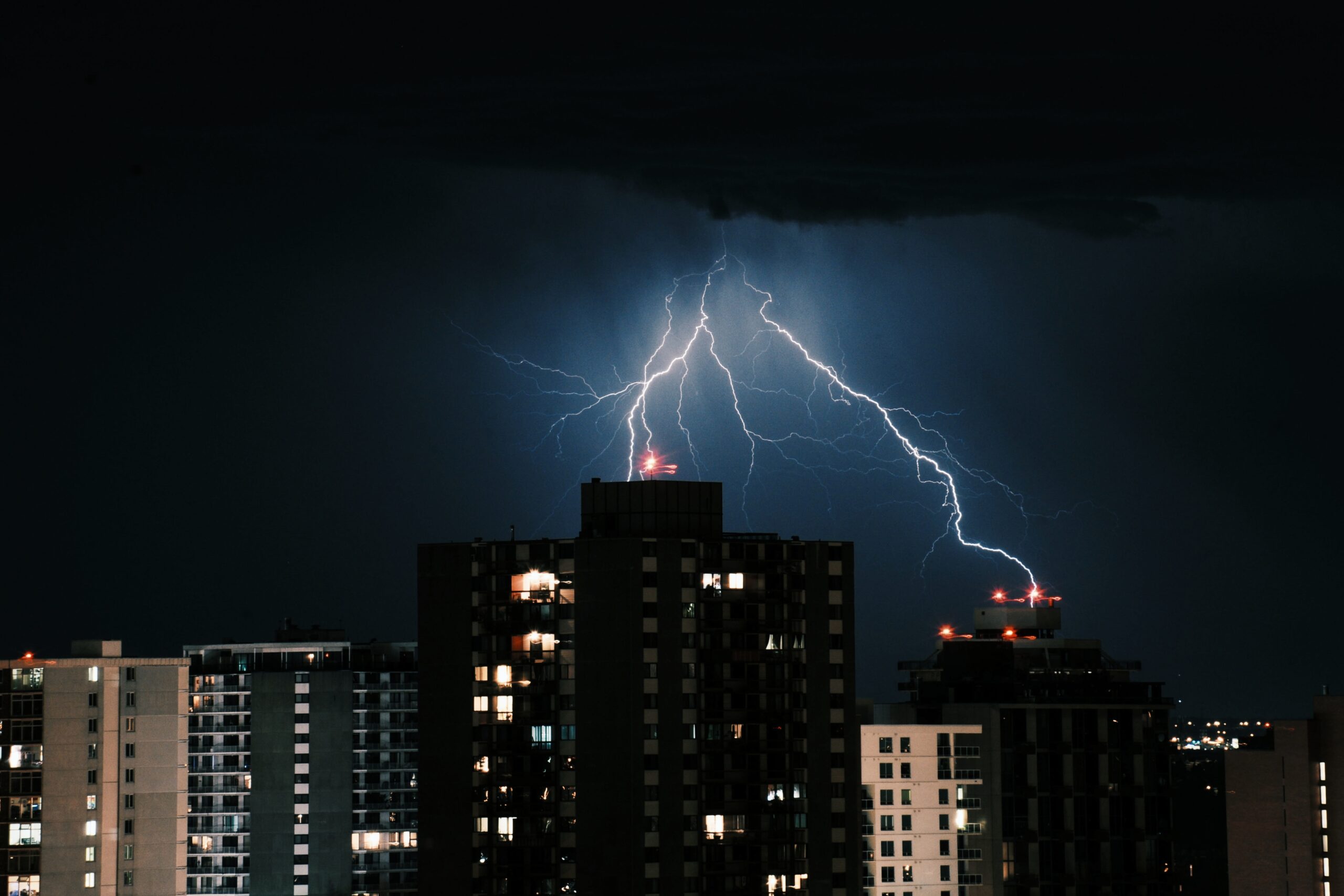 The lightning in the dark sky over the buildings in the city at night